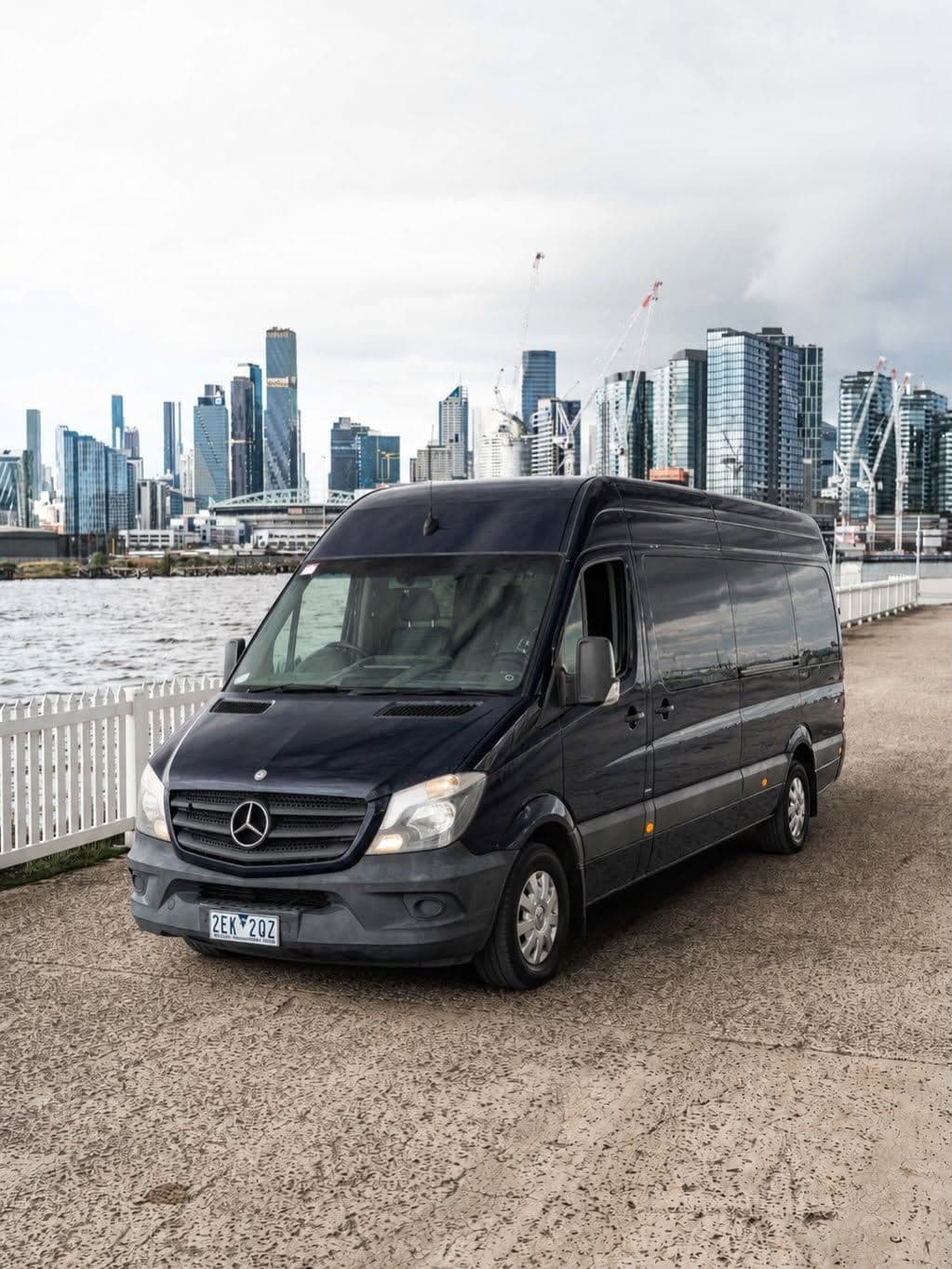 Black Mercedes Sprinter with the Melbourne city skyline at Docklands